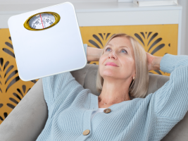 Frau sitzt auf Sofa und schaut nachdenklich entspannt in die Luft und denkt an die Waage